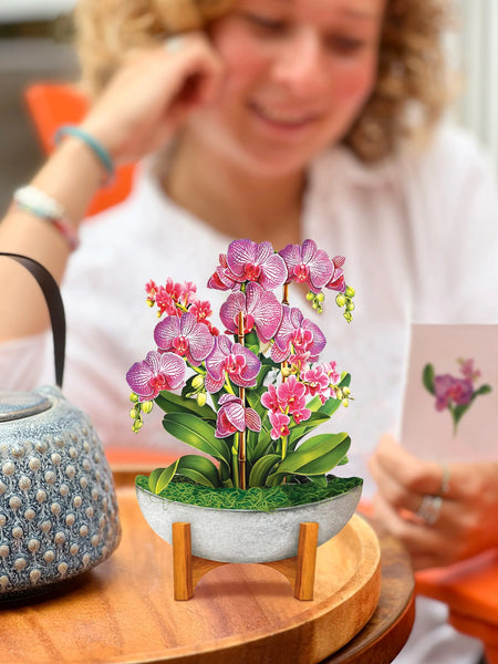 Mini Orchid Oasis greeting card sits on table with model nearby, reading notecard