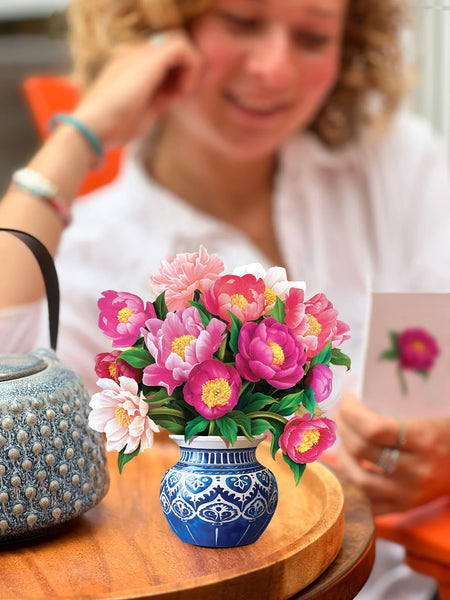 Model reads notecard as greeting card sits on table by teapot