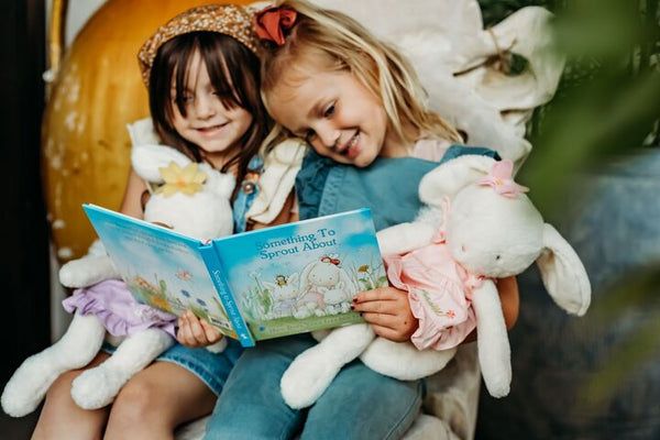 Children reading book and holding plush bunnies