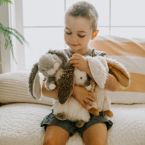 Child sits and hold plush, soft bunnies in his arms. Herby Hare