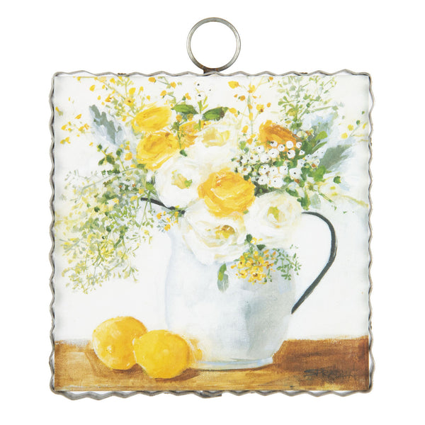 Fresh lemons sit alongside a white pitcher full of yellow and white summer flowers