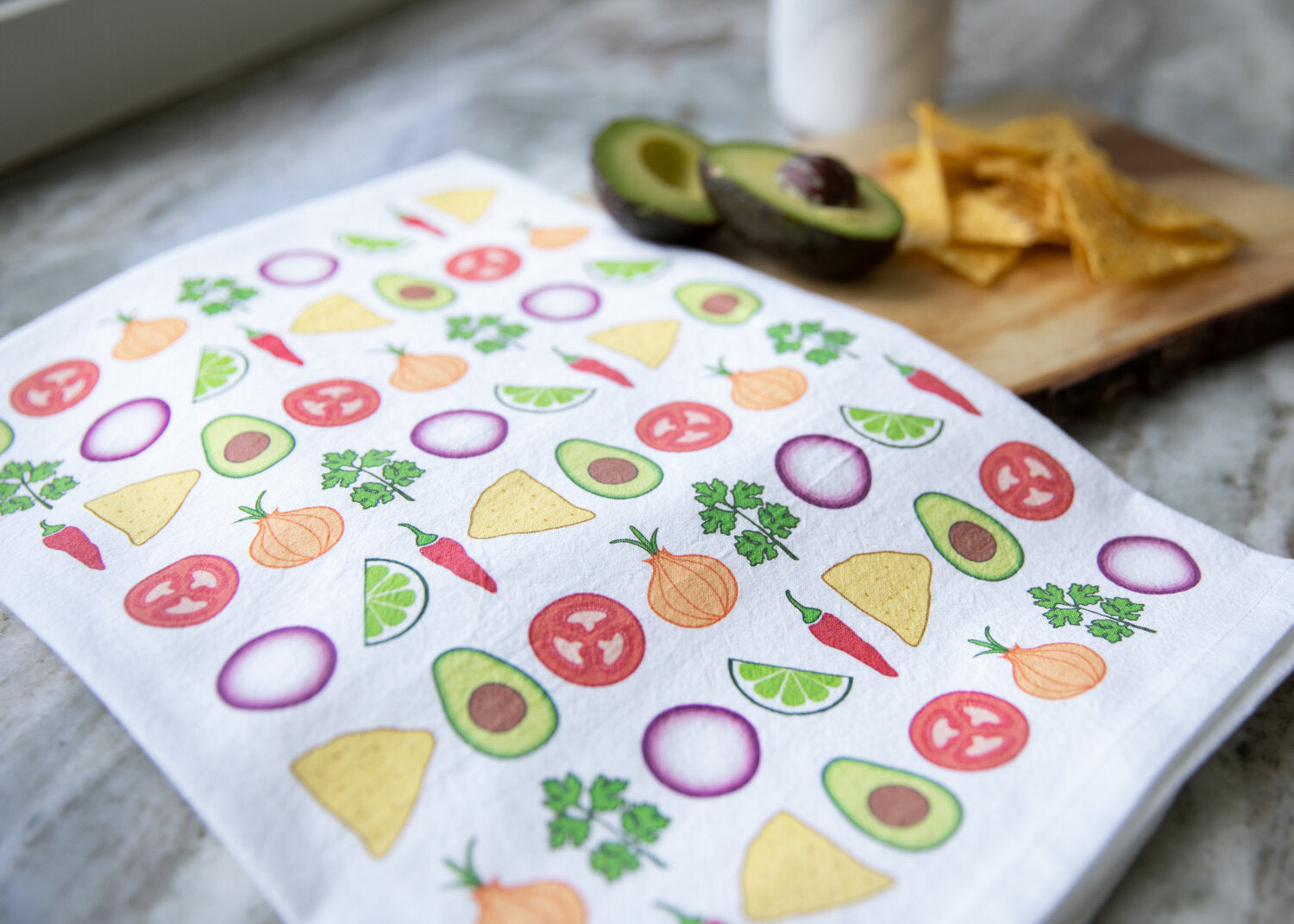 Images of peppers, lime, guacamole, onions and cilantro with tomatoes are printed on this cute flour sack hand towel.