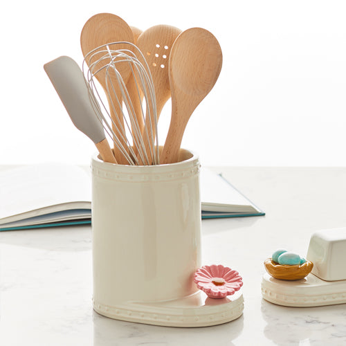 #A041 - Nora Fleming Flower Power mini sits on Utensil Crock filled with wooden spoons, wire whisk and spatula. 