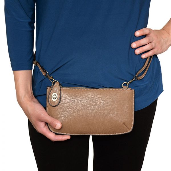 The model in this lifestyle image is wearing a mini Clutch Crossbody Wristlet by Joy Susan